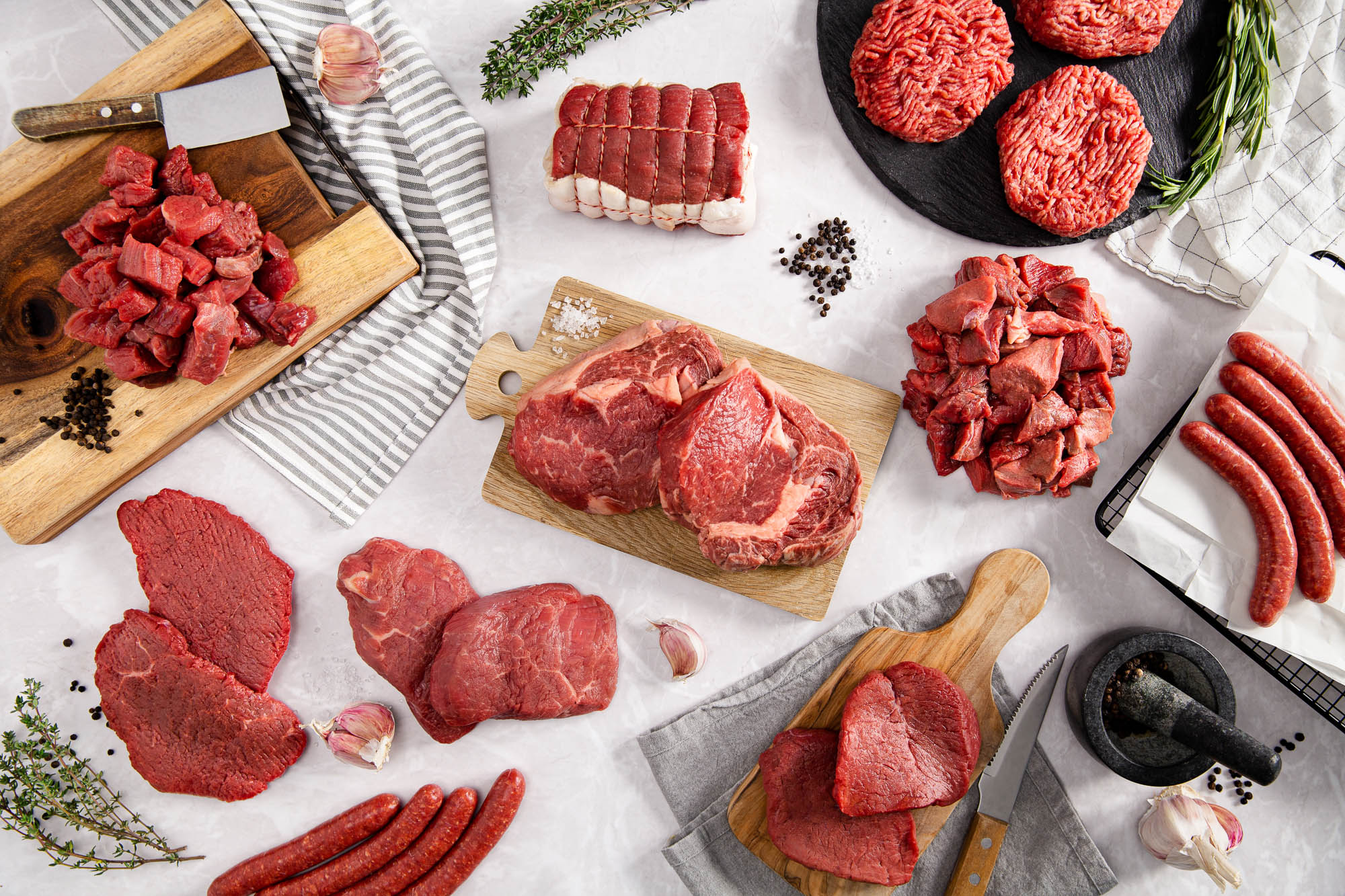 Verschiedene Rindfleisch-Zuschnitte und Hackfleisch auf Holzbrettern arrangiert