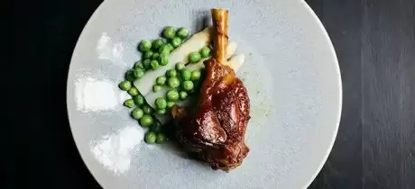 Geit braadschenkels met witte asperges en doperwten