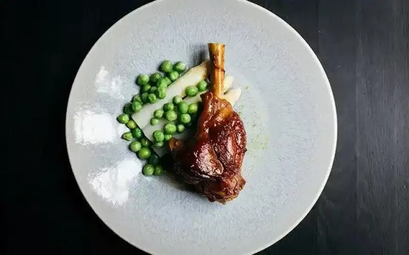 Geit braadschenkels met witte asperges en doperwten