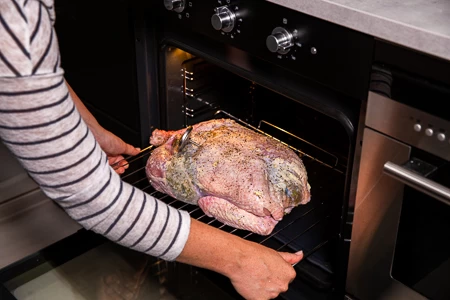 Schuif de kalkoen boven de bakplaat in de oven. Ve