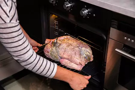 Schuif de kalkoen boven de bakplaat in de oven. Ve